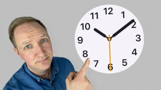 Maximilian Bauer zeigt mit Finger vor grauem Hintergrund auf ein Apple Uhr Zifferblatt